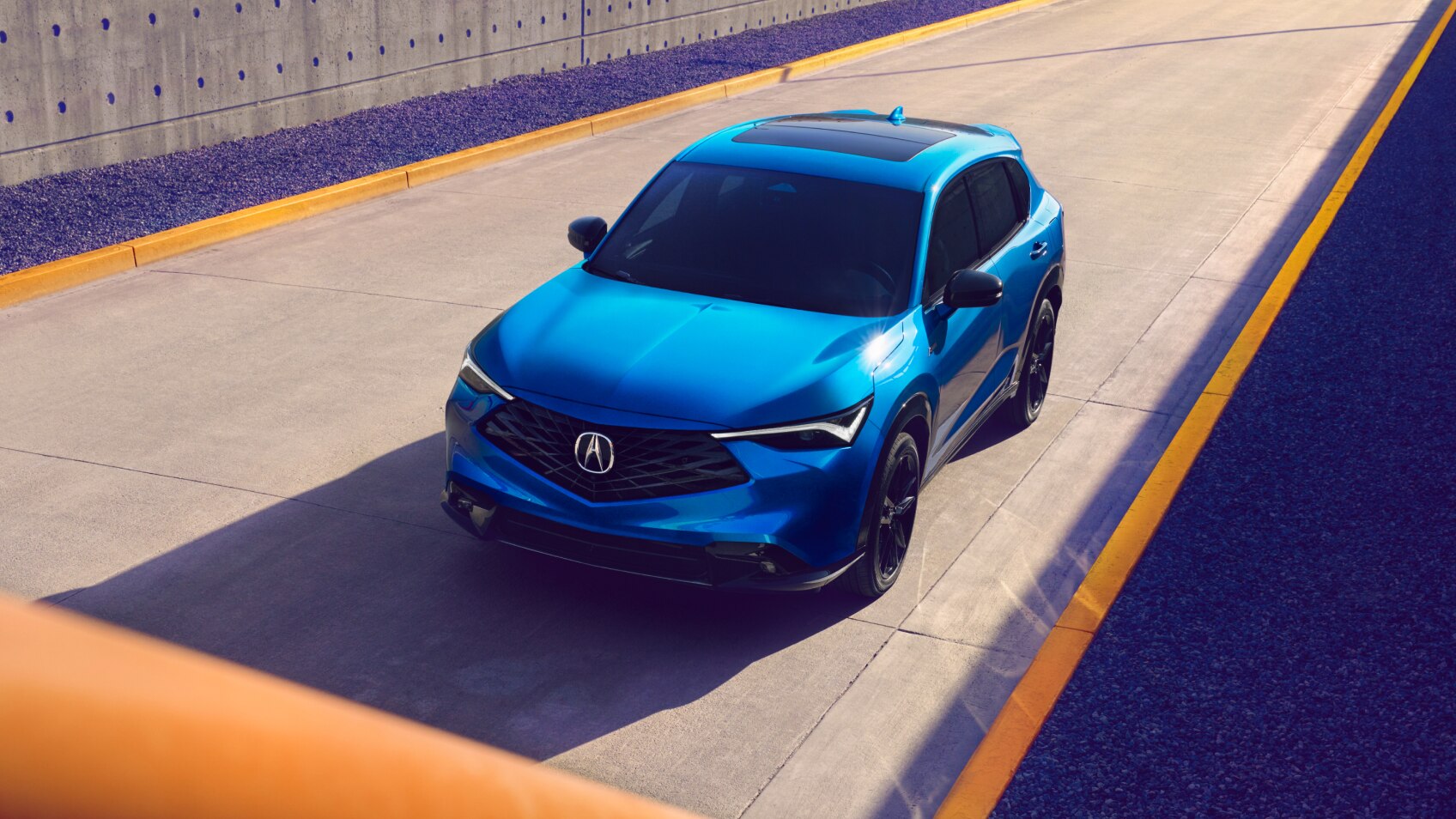 Overhead wide-shot of a blue Acura ADX on a road. 