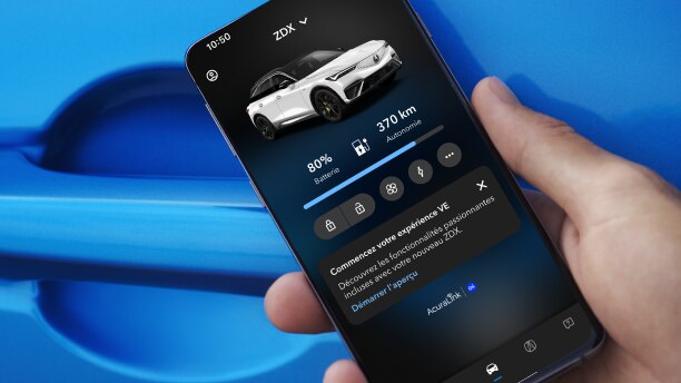 Gros plan d’une main tenant un téléphone intelligent devant la poignée de porte d’une Acura bleue. L’écran du téléphone intelligent affiche une Acura avec les phares allumés et la phrase « Acura. Conduisez comme jamais auparavant. »