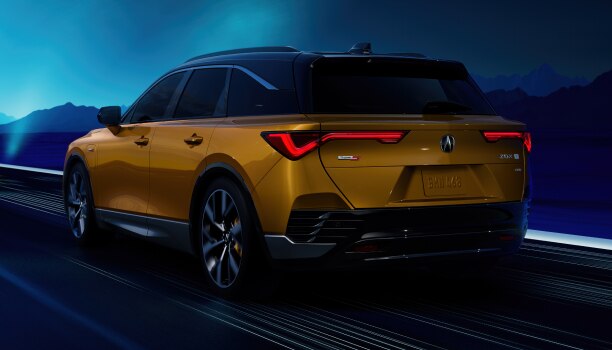 Plan de trois quarts arrière d’un ZDX de couleur or roulant de nuit avec la silhouette d’une montagne en arrière-plan.