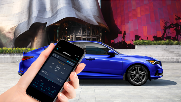 À l’avant-plan, une main tient un téléphone intelligent affichant l’application AcuraLink.