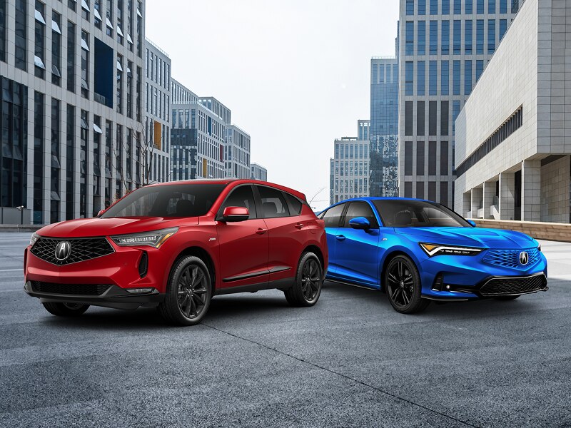 Vue de trois quarts avant d’un RDX rouge stationné entre des immeubles de ville. Un MDX bleu se trouve juste derrière.