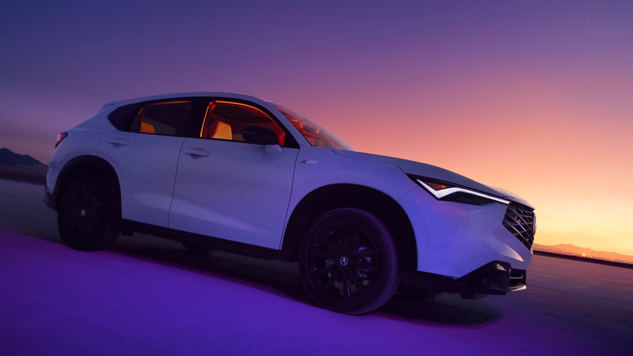 Acura ADX blanc vu de côté avec un coucher de soleil au loin.