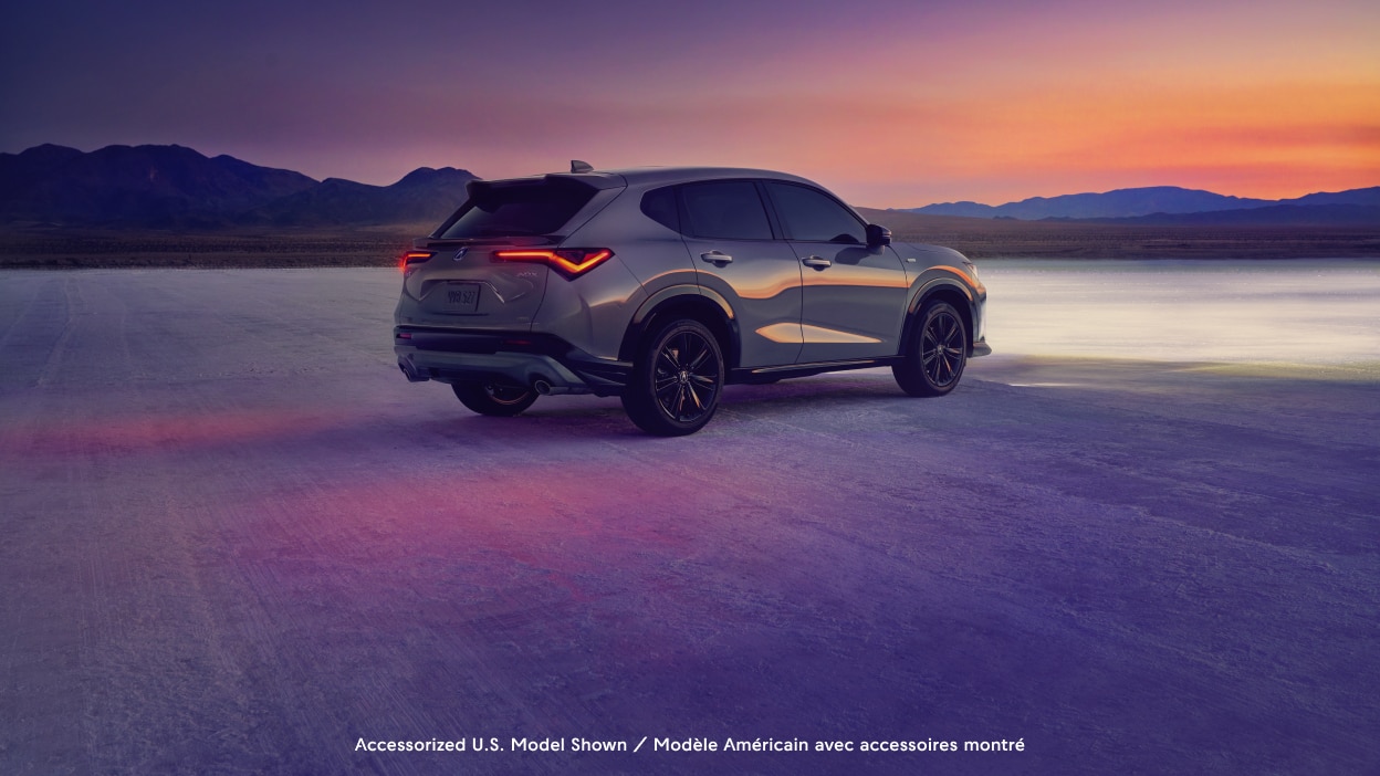 Plan grand angle d’un Acura ADX vu de l’arrière devant un coucher de soleil.