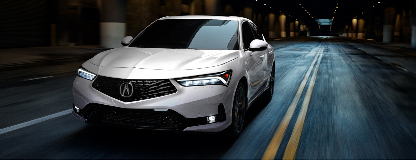 Plan de trois quarts avant d’une Integra blanche circulant sur une autoroute souterraine déserte.