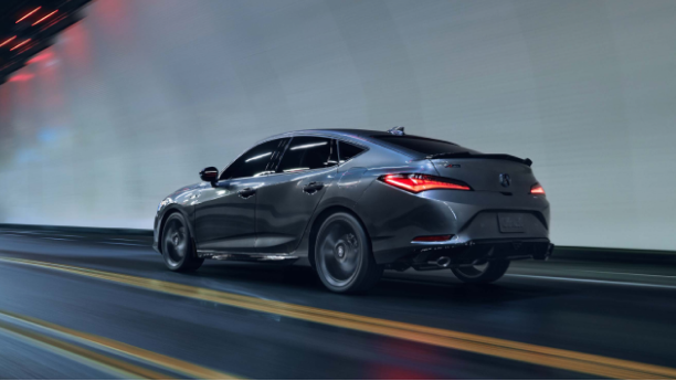 Plan de trois quarts latéral arrière d’une Integra grise roulant dans un tunnel la nuit avec les feux arrière à DEL allumés.