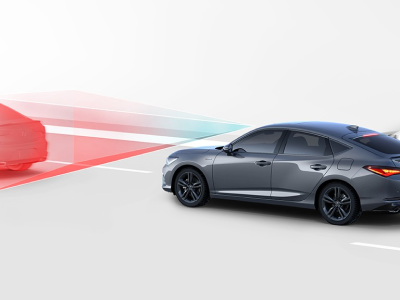 Représentation numérique, où tout est blanc sauf l’Integra. Plan de trois quarts latéral arrière d’une Integra grise roulant sur une route. Des lignes bleues et rouges jaillissent de l’avant de l’Integra pour détecter le véhicule qui précède.