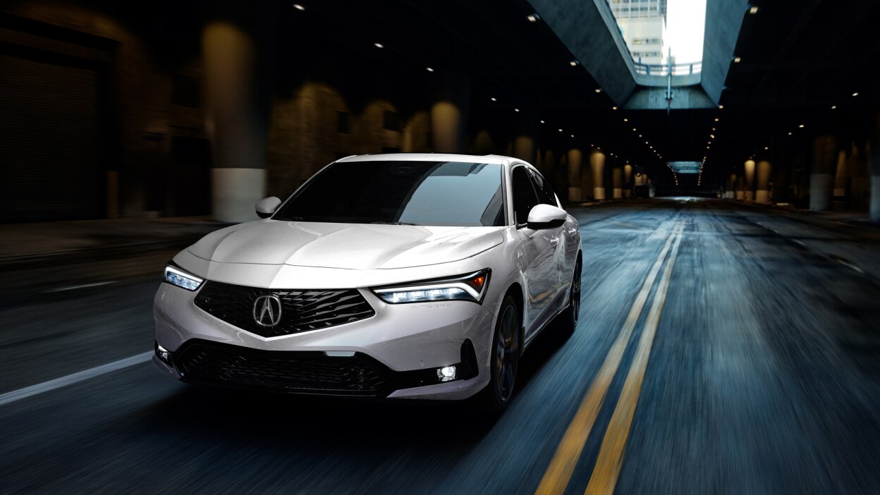 Plan de trois quarts avant d’une Integra blanche circulant sur une autoroute souterraine déserte.