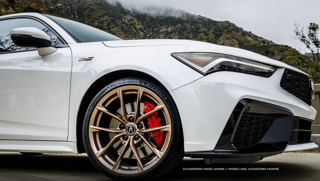 Vue latérale d’une Integra blanche roulant sur une route dégagée. 