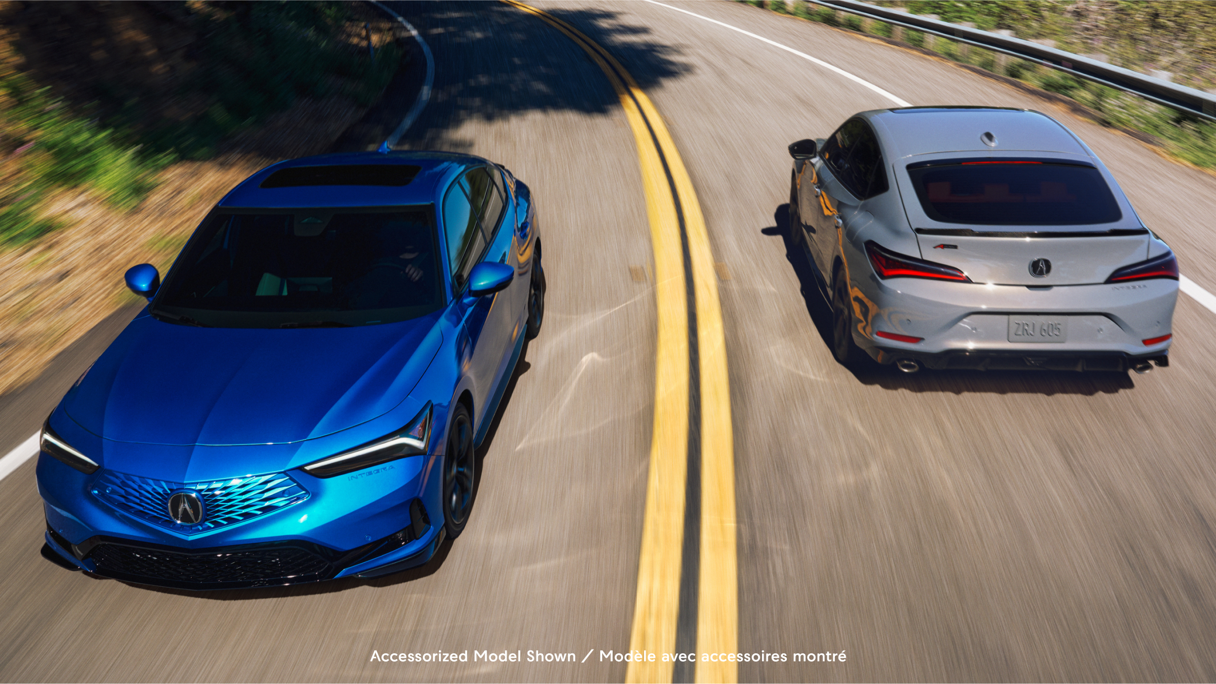 Deux modèles Integra 2023, un de face avec feux à DEL allumés, l’autre en vue arrière avec un homme appuyé contre le véhicule