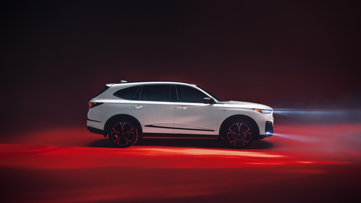 A grey MDX driving down a country road, passing by rows of grapevines.