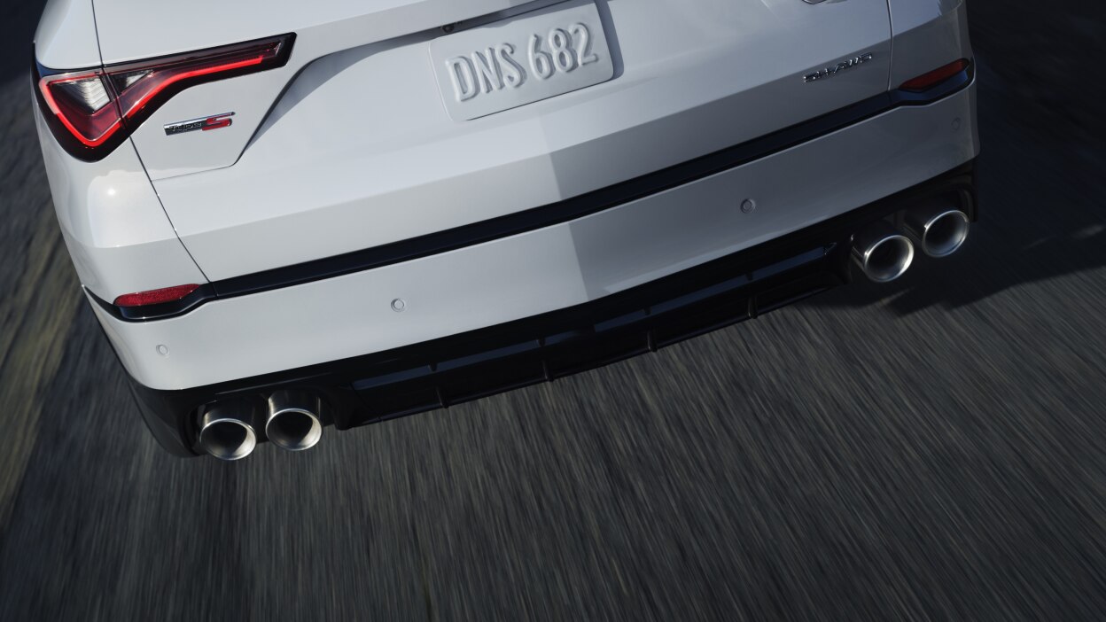 A red MDX taking a corner in the wilderness.