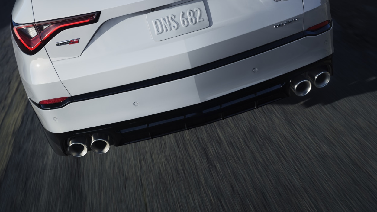 A red MDX taking a corner in the wilderness.