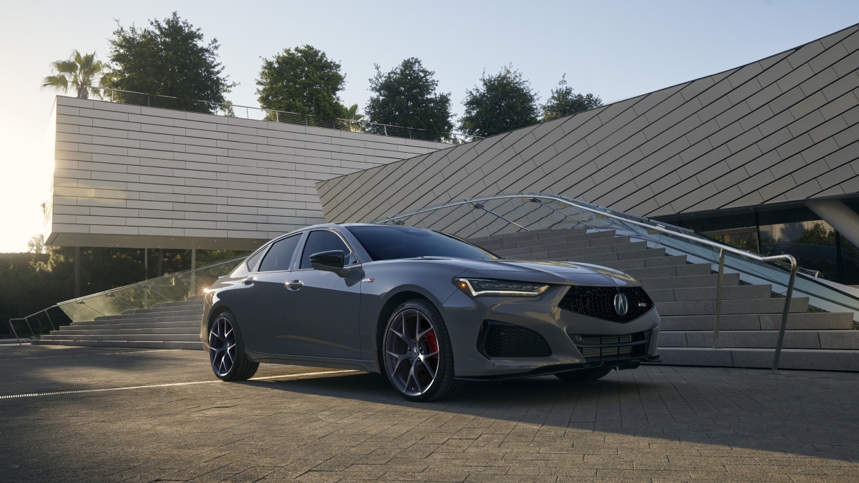 Vue latérale avant en contre-plongée d’une TLX grise stationnée à l’extérieur d’un bâtiment moderne.