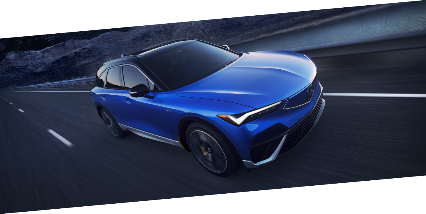 Plan de trois quarts avant en plongée d’un ZDX bleu circulant sur une autoroute désertique au crépuscule.