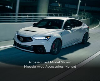 Plan de trois quarts latéral d’une Integra Type S blanche effectuant un virage sur une bretelle d’autoroute la nuit.