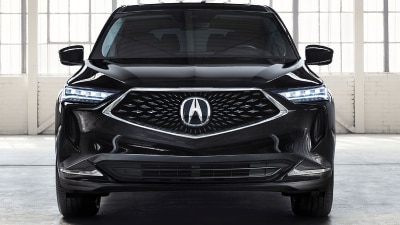 Front-facing shot of a black Acura MDX parked in a large, empty white garage space featuring loft-style windows and white brick walls. Vue avant d’un Acura MDX noir stationné dans un grand garage blanc vide muni de fenêtres de style loft et de murs de briques blanches.