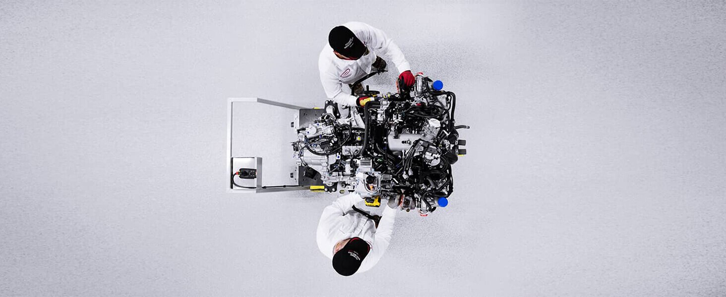 Overhead shot of two Acura engineers in whitespace, working on a futuristic engine.	Vue aérienne de deux ingénieurs Acura dans une salle blanche qui travaillent sur un moteur futuriste.