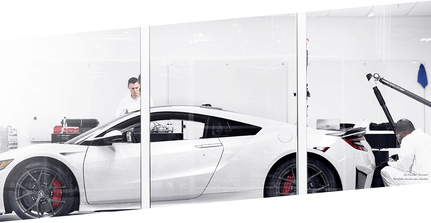 Two technicians work on a white Acura NSX at the PMC. / Deux techniciens travaillant sur une Acura NSX blanche au PMC.