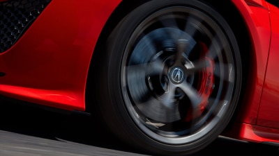 Front wheel spinning of a red NSX as it is driven on the road. // Roue avant d'une NSX rouge qui tourne en roulant sur la route