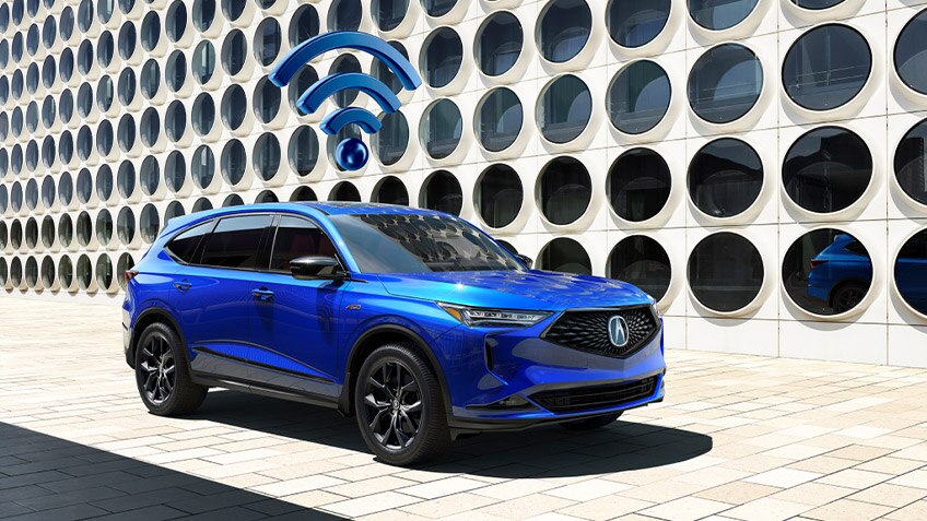 A blue wifi icon floating above a blue Acura MDX parked in front of a futuristic building. // Une icône wifi bleue flottant au-dessus d'un Acura MDX bleu stationné devant un bâtiment futuriste.